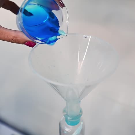 researcher pours blue liquid into watering can placed in the bottle. examination of diapers in the enterprise