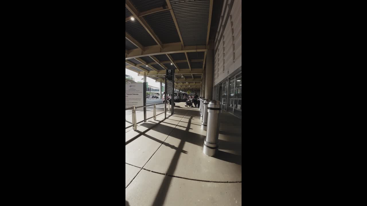 Caminando por una acera cubierta fuera de la terminal del aeropuerto.