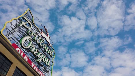 4k trucking shot from under portland oregon old town sign revealed frame left with overhanging tree frame right with partly cloudy sky