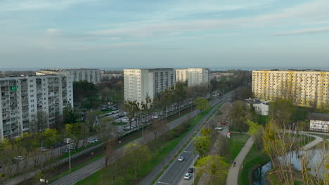 aerial view of a suburban residential area in żabianka, gdańsk, with large apartment buildings flanking a road amidst green spaces and trees, under a soft evening sky