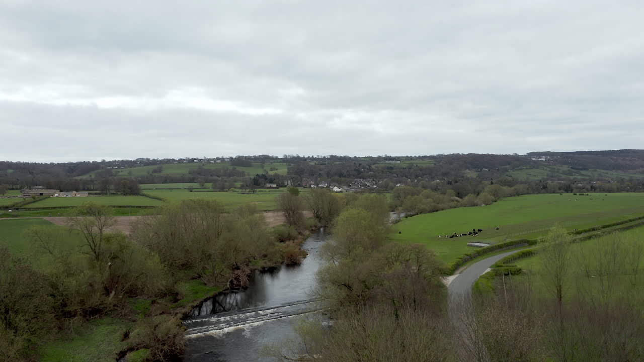 Ripresa aerea ascendente che rivela una strada di campagna, un fiume e campi nel North Yorkshire, in primavera.
