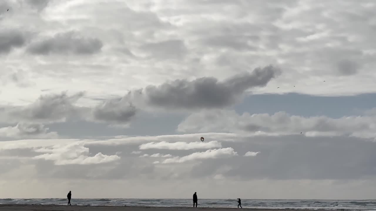 Family Silhouette At Beach With Kid Flying Kite On Sunny Day. wide shot