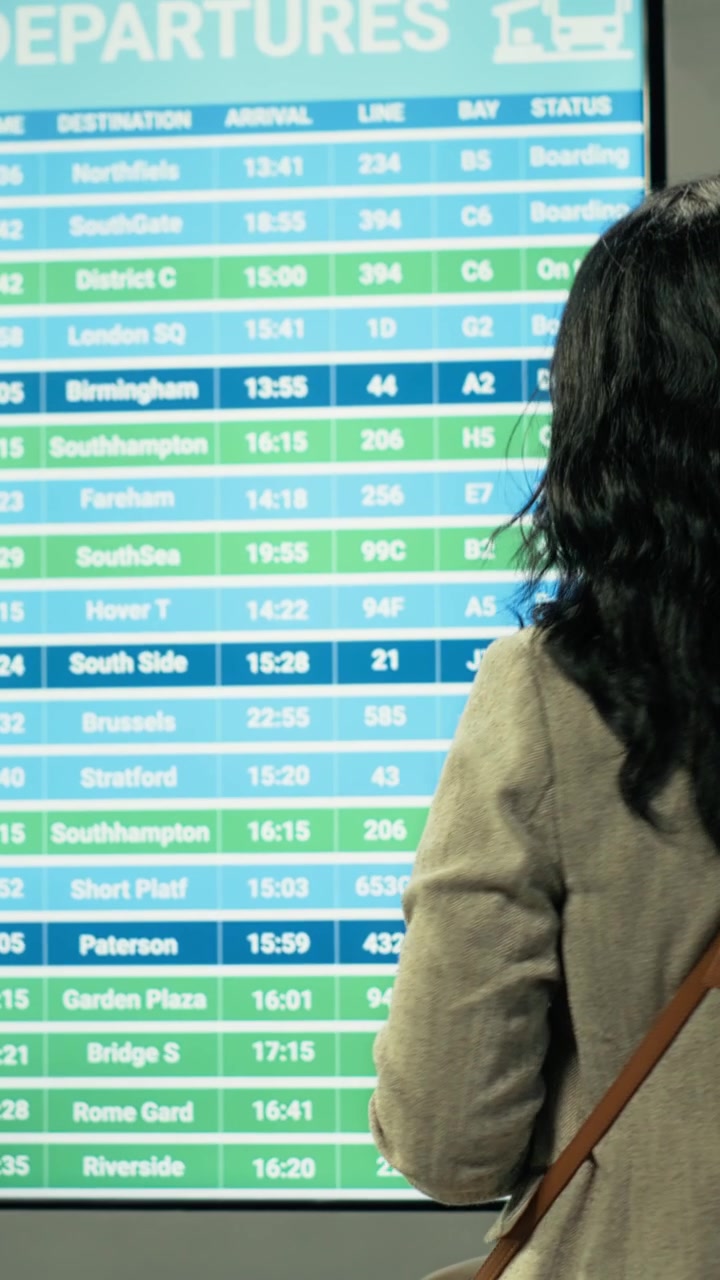 Pasajera verificando la hora de salida y el horario en la pantalla de información