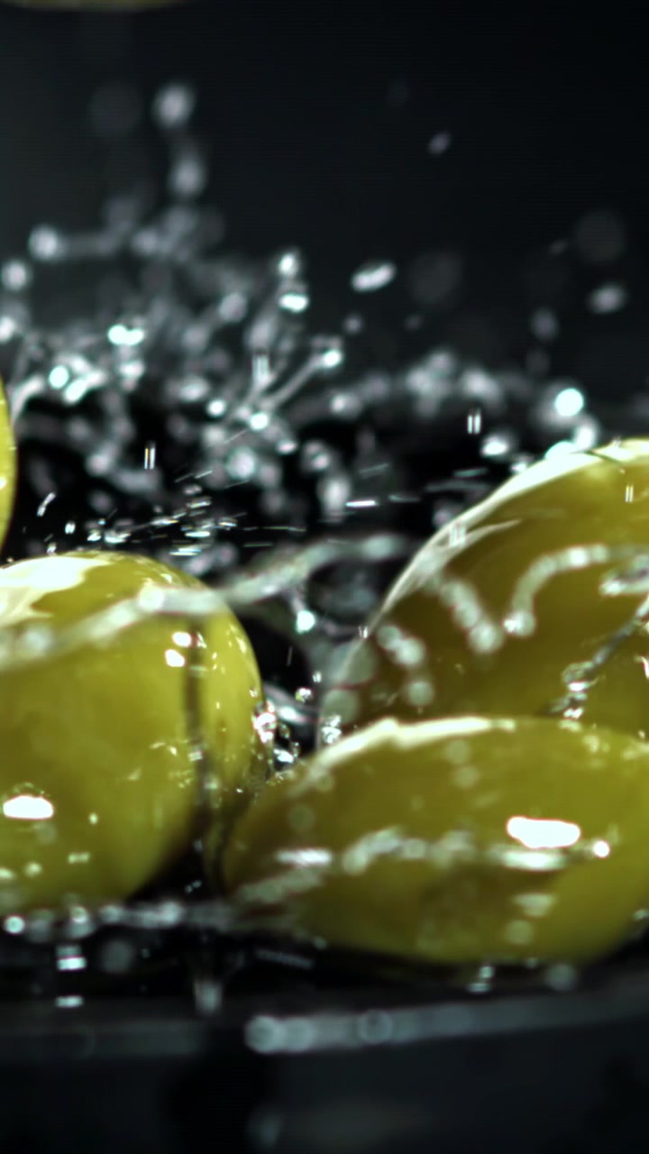 Olive verdi fresche che cadono nell'acqua con schizzi