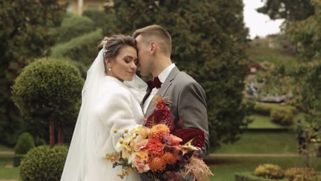 Newlyweds,-caucasian-groom-with-bride-walking,-embracing,-hugs-in-park,-wedding-couple