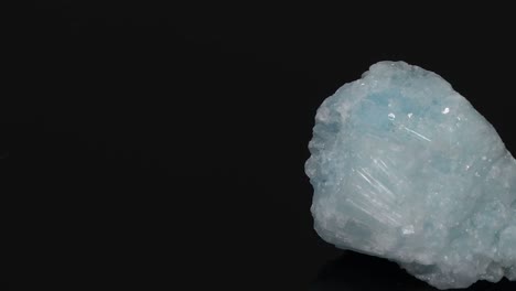 a detailed view of a blue mineral fragment rotating against a dark background, showcasing its texture and color.