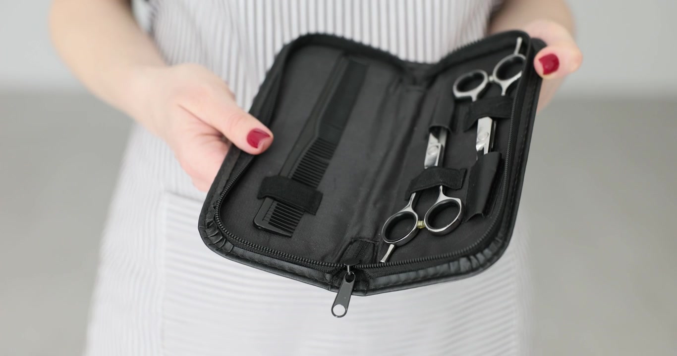 Hairdresser opens leather case with hairdressing scissors