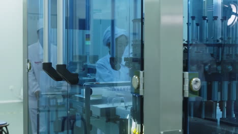 scientist or worker woman in uniform works on a vial filling line. production of medical dietary supplements, glass bottles of medicine or vaccine on a conveyor belt product line at pharma factory