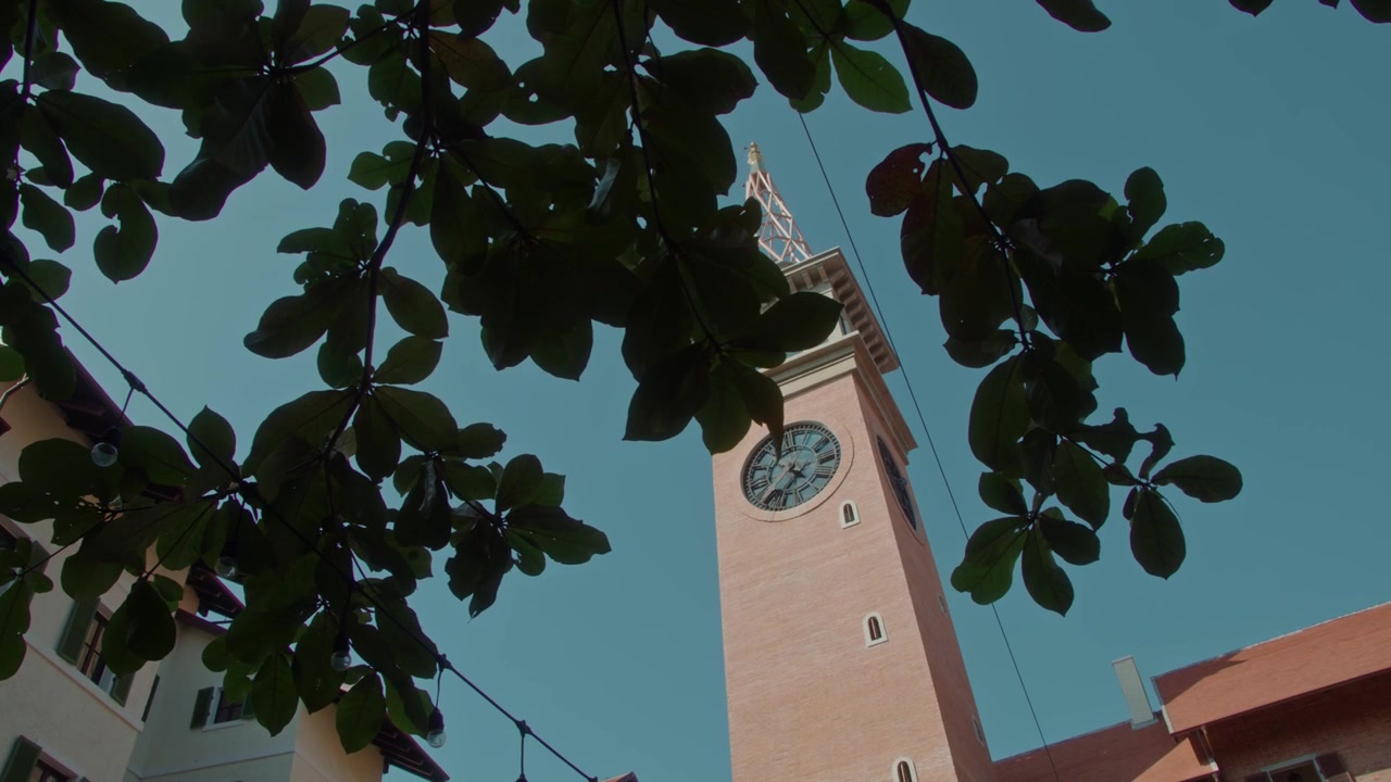 Vista dal basso di una torre dell'orologio in mattoni contro un cielo azzurro limpido