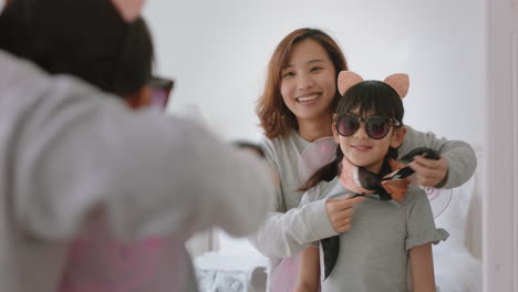 asian mother and daughter playing dress up game at home little girl having fun with mom enjoying playful day with child together on weekend happy family 4k footage