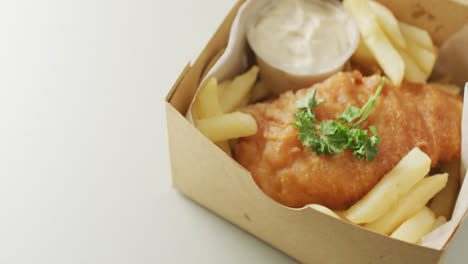 Video-of-fish-and-chips-with-dip-in-takeaway-food-box,-with-copy-space-on-white-background