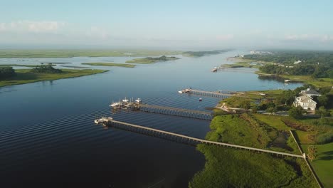 Peaceful-sunrise-flyover-of-piers,-houses,-and-marsh-at-Trails-End-Park-in-Wilmington-North-Carolina