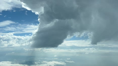 cloudscape pov immersive view from an airplane cabin while flying across a blue sky with some stormy clouds ahead