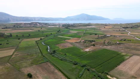 farmland and farming fields situated near the sea with mountains in the background