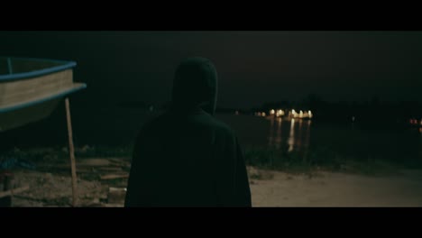 person walking by a lake at night