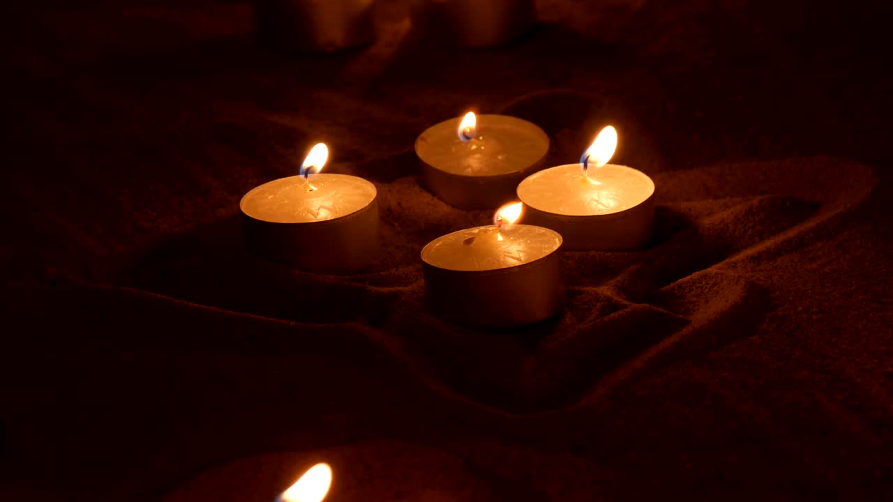 Candele rotonde che bruciano nella sabbia