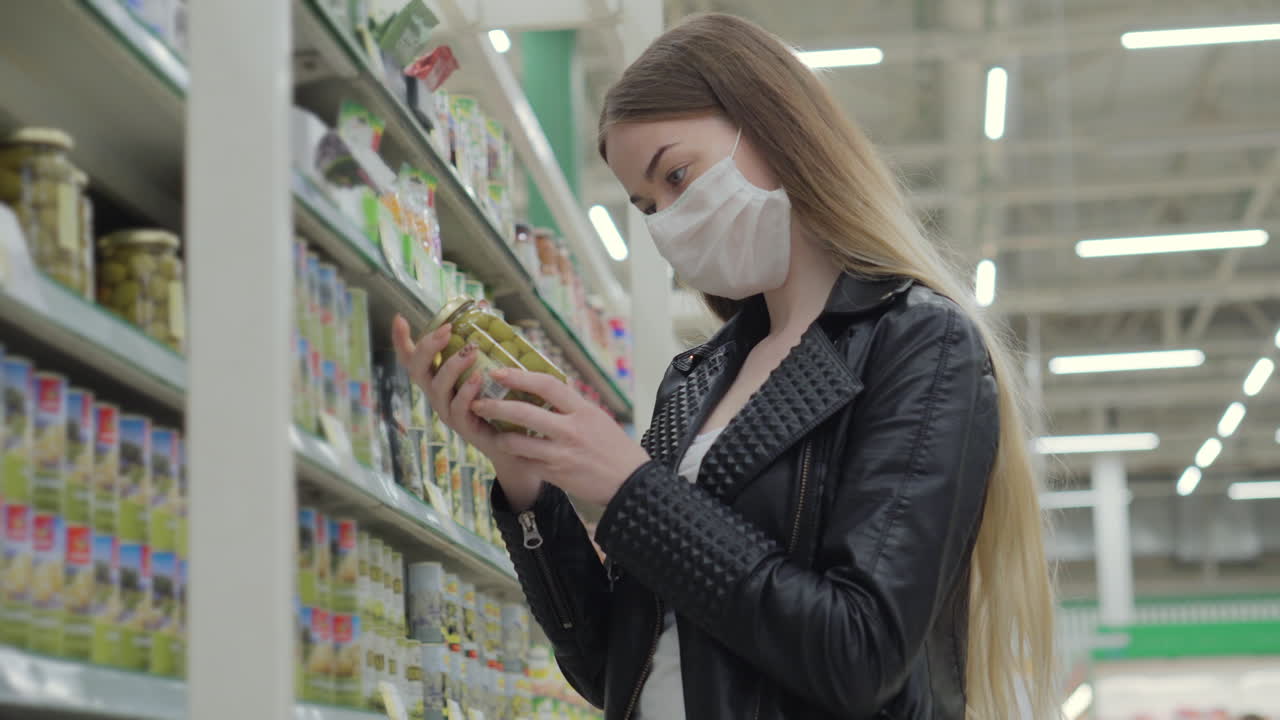 마스크를 착용 한 여성이 슈퍼마켓에서 올리브를 구입하고 있습니다.