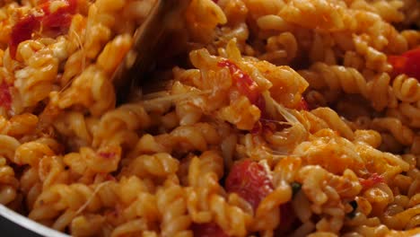 mouthwatering close up shot, stirring creamy and cheesy pasta with tomato sauce using wooden spatula, stretching melted mozarella cheese