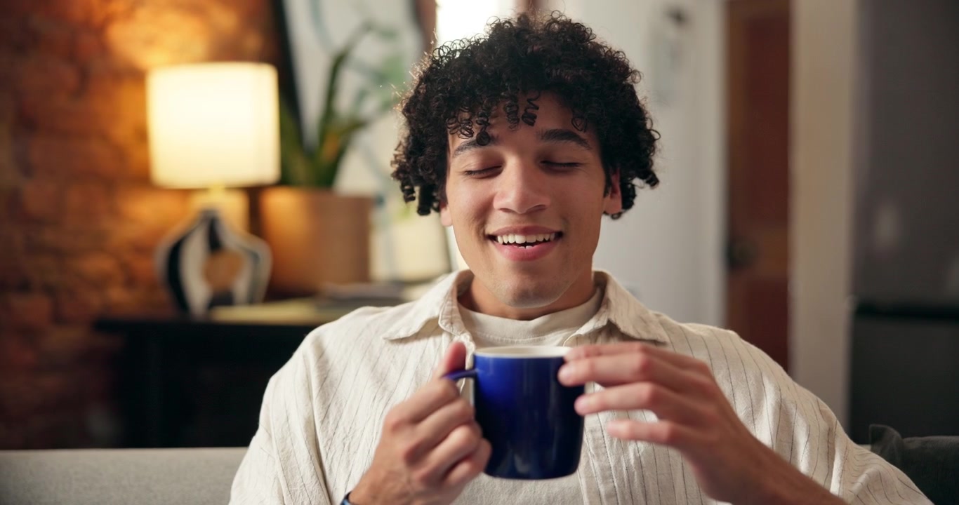 Giovane uomo che gusta una tazza calda di caffè a casa