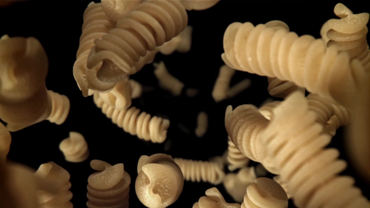 Fusilli secchi che cadono al rallentatore su sfondo nero