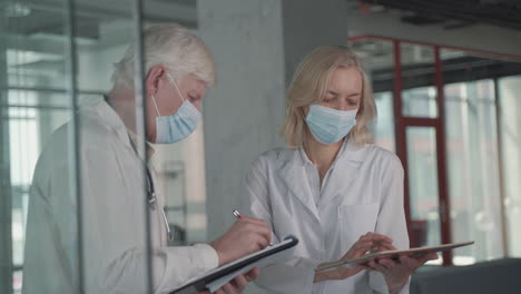 a pair of doctors with masks converse while looking at results on a tablet 2