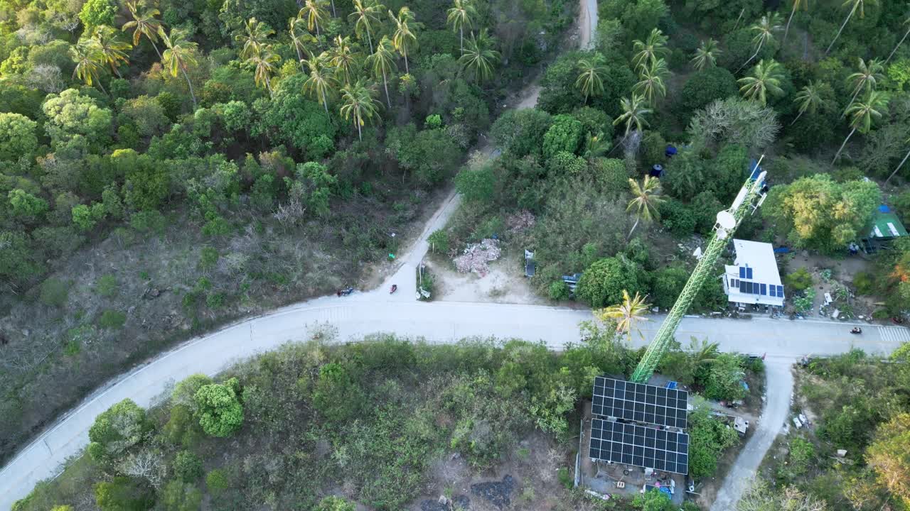 Droneflyvning over junglebakke med solcellehuse, veje, motorcykler i Koh Tao, Thailand