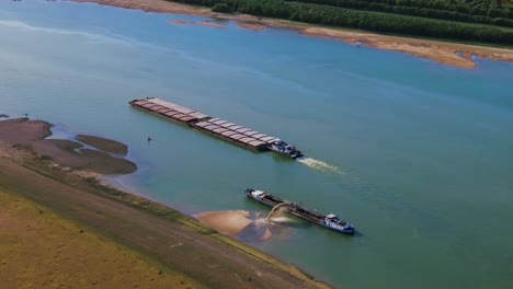 aerial shot of a dredger unloading dredged sand on a big river, other ships passing by, sunny day