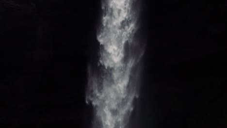 slowmotion shots of remote icelandic waterfall with man walking towards it