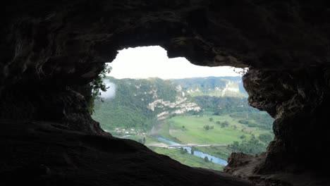 view from rocky cave on green forested valley and river