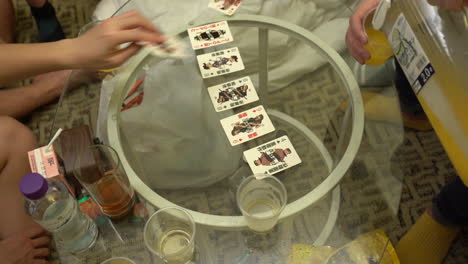 unidentifiable asian people play a typical card game in hong kong, on a glass table