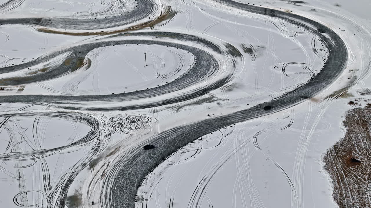 Aerial footage of a frozen race track with cars sliding around