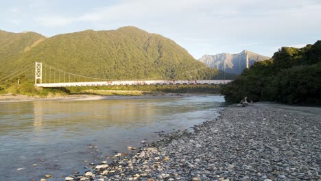 Rusty-suspension-bridge-in-mountains-at-sunset