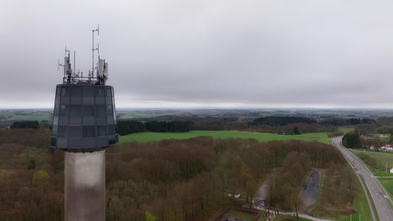 Aerial drone shot of a tall observation tower with a glass top, countryside on a cloudy day