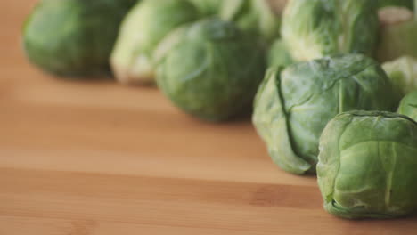 slow motion panning left to right across fresh green brussels sprouts on wooden tabletop