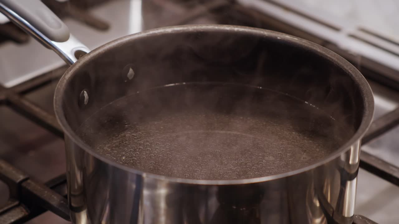A close-up of steam coming off a boiling pot of water on a clean and modern kitchen stove