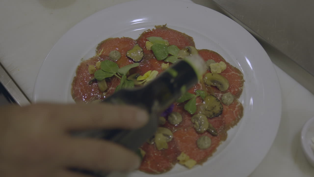 vista de cerca de un cocinero experto llueve delicadamente una corriente de aceite de oliva dorado sobre la pizza recién preparada