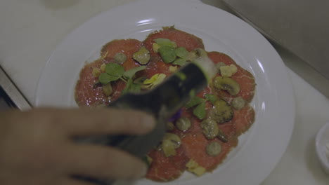 vista de cerca de un cocinero experto llueve delicadamente una corriente de aceite de oliva dorado sobre la pizza recién preparada