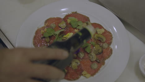 close view of skilled chef delicately drizzles a stream of golden olive oil over the freshly prepared pizza