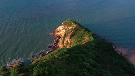 lush tropical lantau island hilltop slope to ocean coastline aerial rising pull back