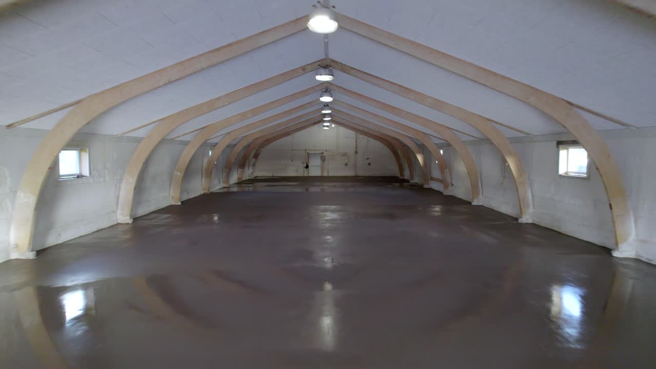 Wide empty industrial building hall with newly finished epoxy concrete floor, smooth drone dolly