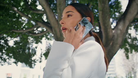 luxurious woman speaking telephone walking under tree close up. lady calling