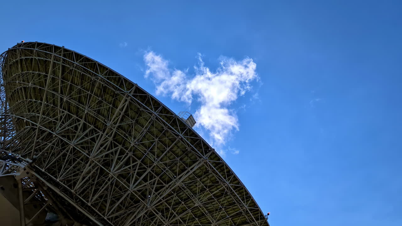 Large Satellite Dish Against Blue Sky with Clouds