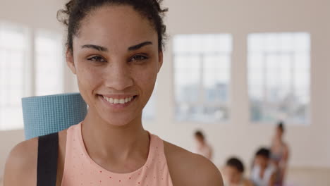 retrato hermosa mujer de yoga de raza mixta sonriendo con confianza disfrutando de un estilo de vida saludable con gente practicando en el fondo del gimnasio