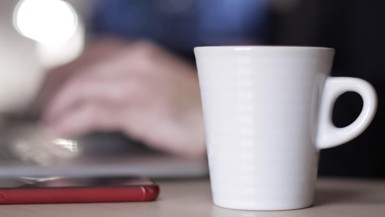 남자는 차 한 잔을 마시며 사무실에서 노트북으로 일한다