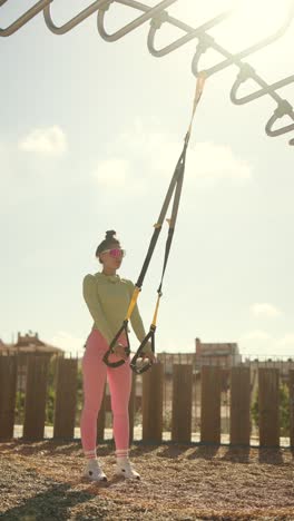 woman exercising with trx suspension trainer outdoors