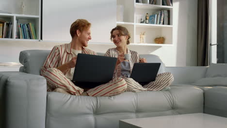 happy couple using laptops resting on weekend. young people work in home office