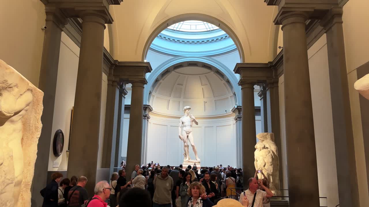 Michelangelo's sculpture David stands majestically as people walk through Accademia art gallery, Florence, Italy