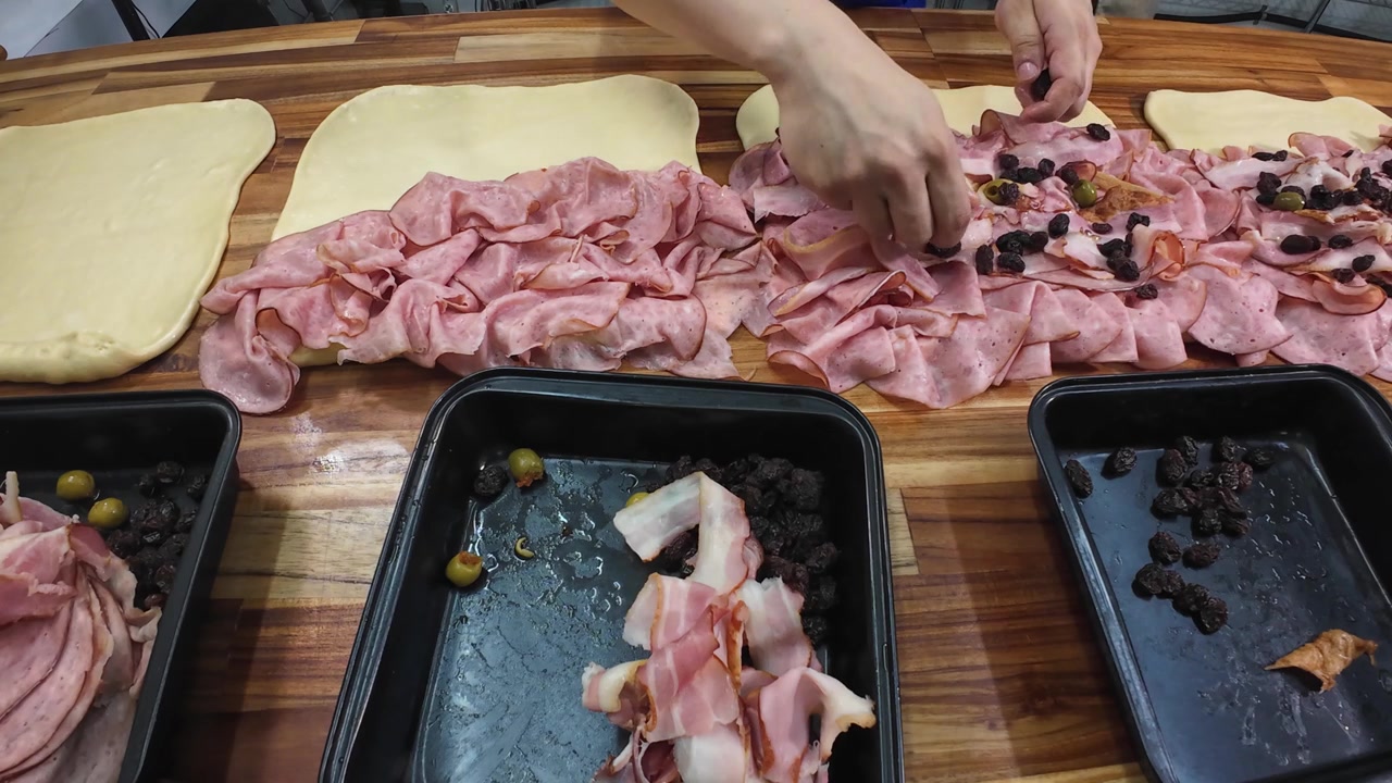 Mani dello chef che aggiungono uvetta nella preparazione del pan de jamón, cibo festivo tradizionale venezuelano.