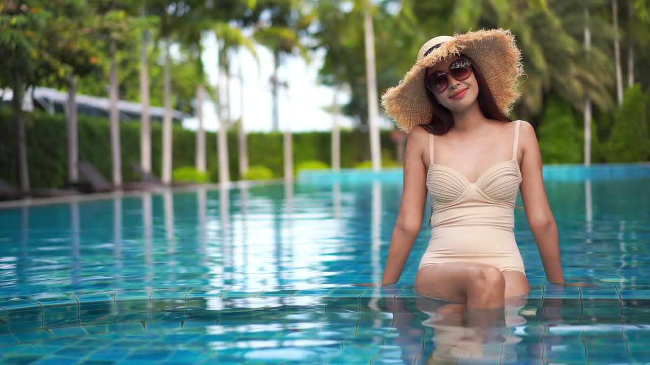 고급 호텔 리조트에 있는 크리스탈 블루 수영장에서 휴식을 취하고 있는 웃고 있는 아시아 여성