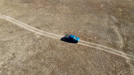 truck driving along a four-wheel dirt trail in a desert - aerial view